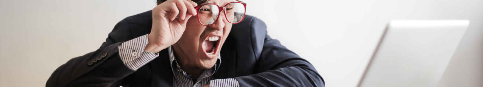 A man who has made a mistake is shouting at a laptop